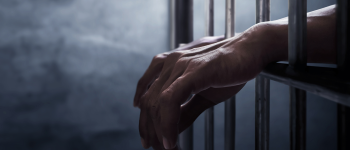 Hands resting on prison bars