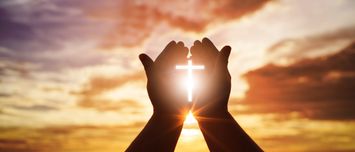 Hands holding a shining cross